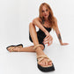 Beige leather platform sandals styled with a black mini dress in a white studio