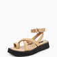 Three-quarter view of beige leather sandals with padded toe loop and black flatform sole
