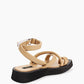 Rear view of beige crossover sandals showing ankle wrap and silver-tone D-ring