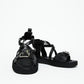 Front view of black leather sandals showing wide buckle straps and crossover construction