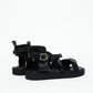 Rear side view of black leather harness sandals with structured heel panels