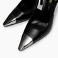 Close-up of polished metal toe caps on black leather pointed slingback heels