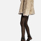 Black leather wrap heels styled on a model with tights and a beige coat, full-length view