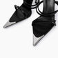 Close-up of black leather straps, small buckles and mirrored pointed toe caps