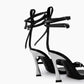 Rear view of black leather wrap heels showing sculptural flared heels and ankle straps