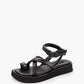 Three-quarter view of black leather platform sandals with crossover straps and toe loop