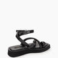 Rear side view of black leather sandals showing padded ankle strap and sculpted platform