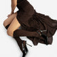 Black patent slingback heels styled on a model in a dark brown dress, overhead fashion view