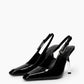 Pair of black patent leather slingback pumps with sculptural transparent heels, three-quarter view