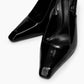 Close-up of glossy black patent slingback heels with elongated square toes