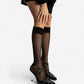 Black patent leather spiked heels worn with sheer black knee-high socks