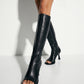 Black peep-toe knee-high boots worn in a studio fashion look