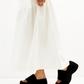 Black textile platform slides styled on a model with an ivory skirt, side view