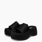 Pair of black platform slides with wide matte textile bands, three-quarter view