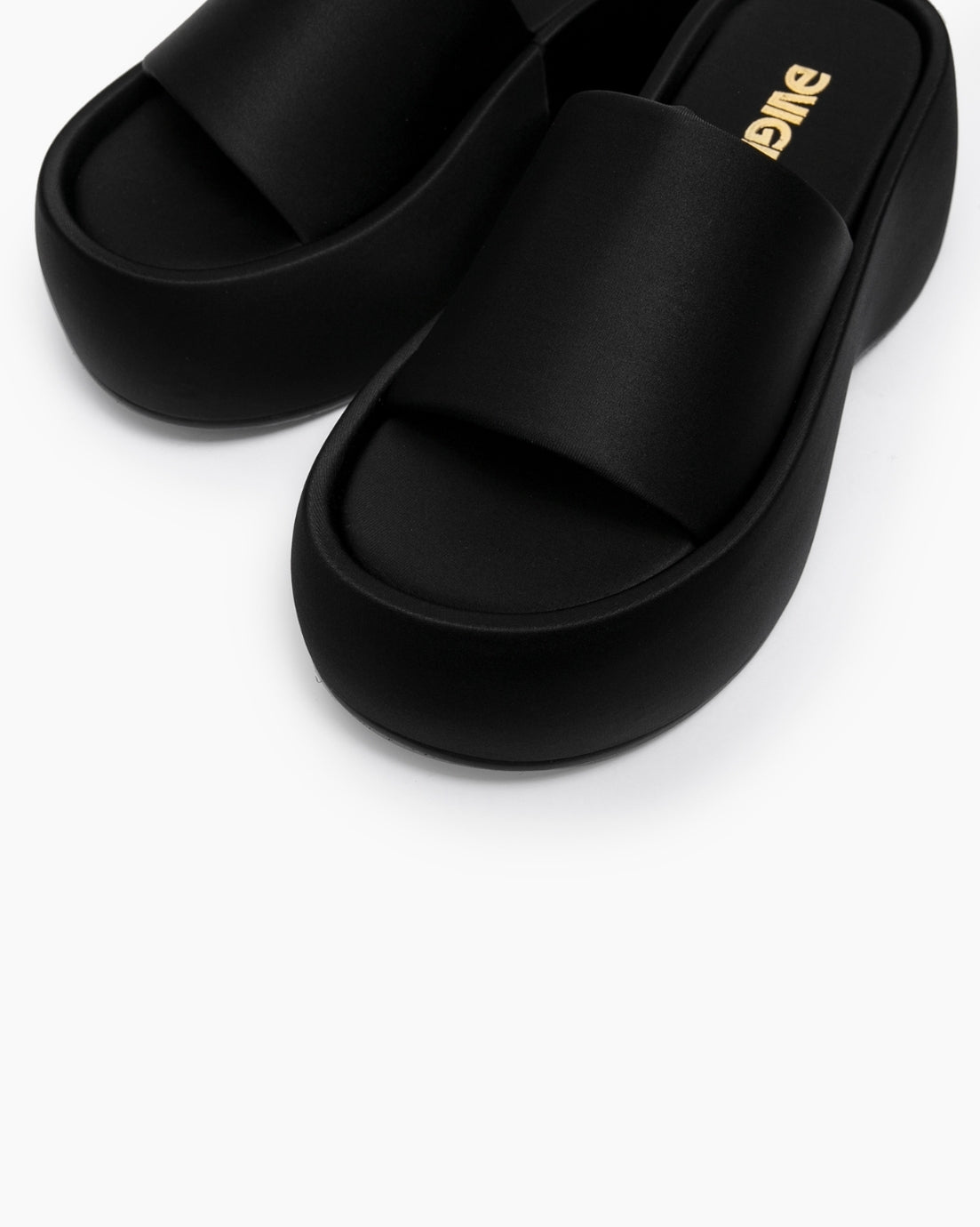 Close-up of black platform slides showing the broad textile strap and footbed
