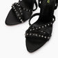 Close-up of black leather cross straps with round silver-tone studs and squared open toes