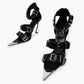 Top view of black leather buckle heels with chrome-coated pointed toe details