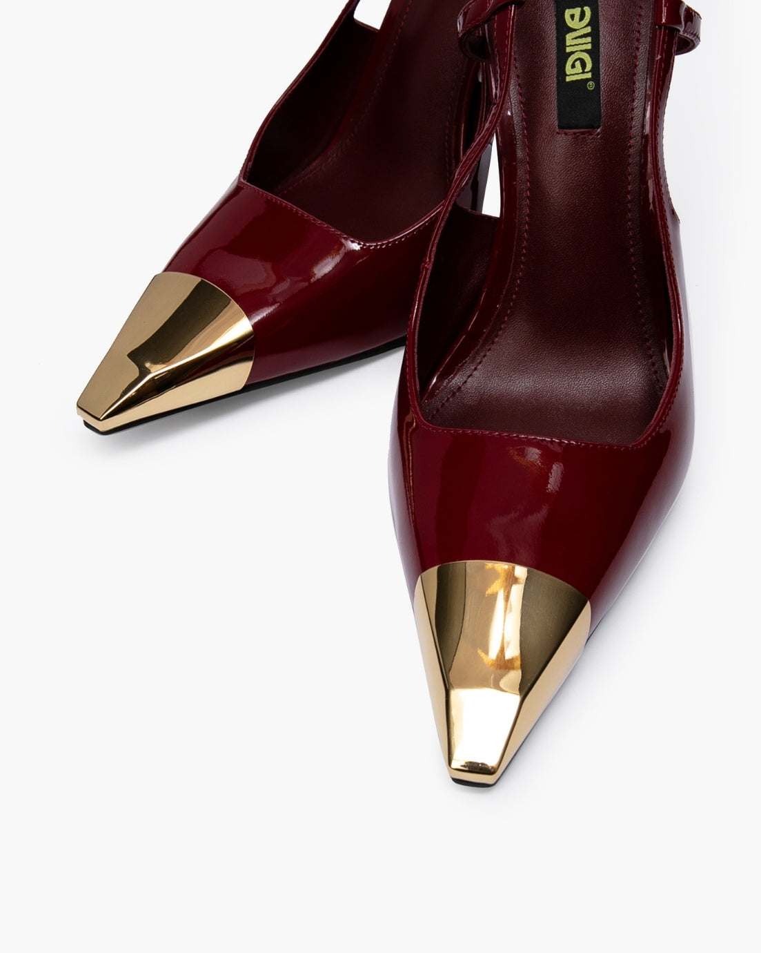 Close-up of glossy burgundy patent leather and sculpted gold-tone toe hardware