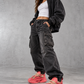 Model wearing coral chunky sneakers with black streetwear in a gray studio