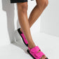 Woman wearing hot pink padded leather sandals in a white studio
