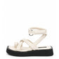 Ivory leather toe-loop flatform sandal with padded crossover straps and black sole, side view