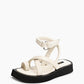 Front three-quarter view of ivory leather sandals with toe loop and sculpted black flatform