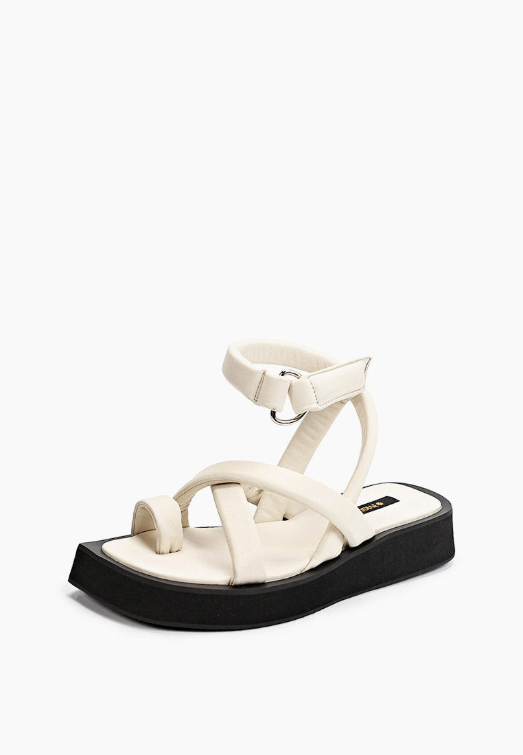 Front three-quarter view of ivory leather sandals with toe loop and sculpted black flatform
