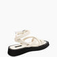 Rear three-quarter view of ivory crossover sandals with wrapped ankle strap