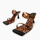 Leopard-print leather and silicone strap heels, front three-quarter view