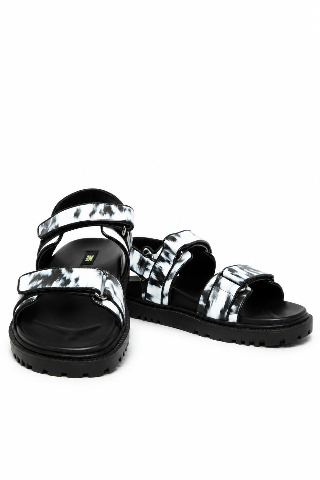 Front angle of black and white brush-print leather sandals with adjustable tabs