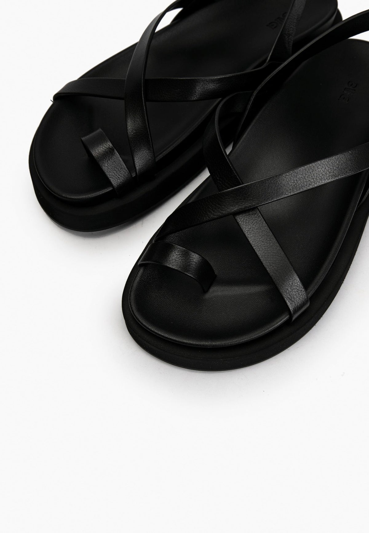 Close-up of smooth black leather straps and cushioned footbed