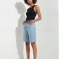 Woman wearing black toe-loop leather flatform sandals with denim shorts in a white studio
