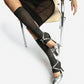 Silver spiked leather heels styled on a seated model with a black skirt and grey knee-high socks
