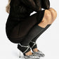 Silver ankle-strap heels worn with a sheer black skirt, front view