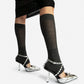 Silver spiked heels on a standing model, showing the buckled ankle straps and open backs