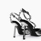 Rear close-up of reflective angular heels and silver spiked ankle straps