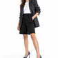 Model in an oversized blazer and Bermuda shorts wearing blue zebra-print pumps